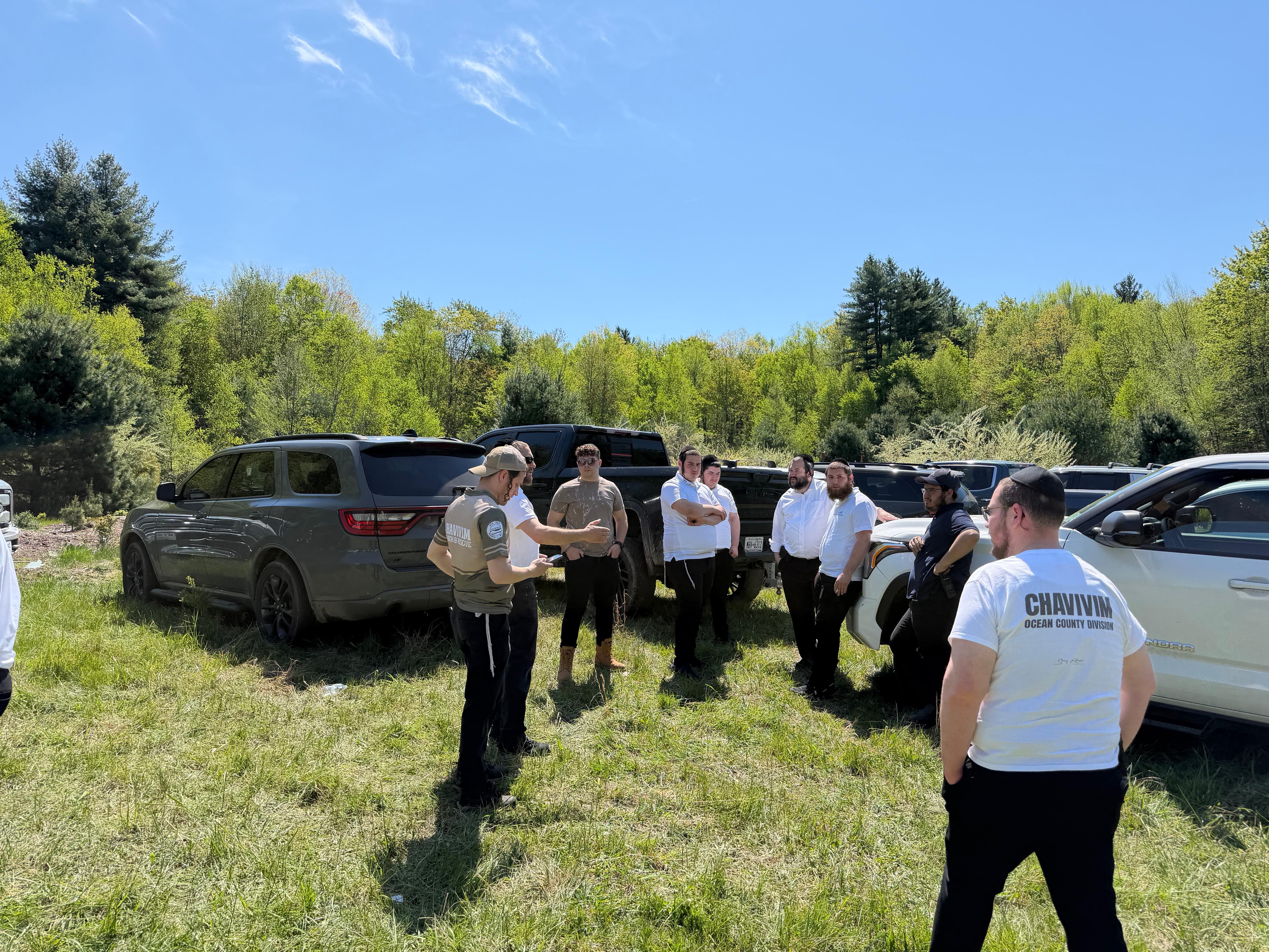 Cross-division Chavivim briefing circle in a Catskills clearing with members from KJ, Rockland, Catskills, Ocean County, Boro Park, and Williamsburg